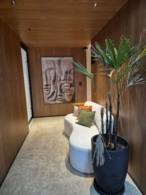 Recepção com sofá branco e quadro de rostos